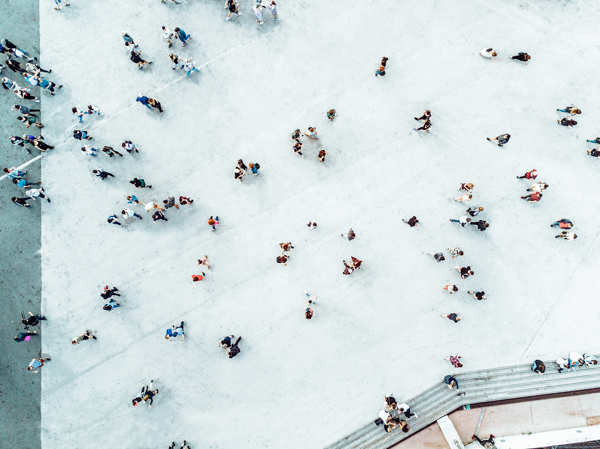 Overhead view of many people walking on concrete walkway